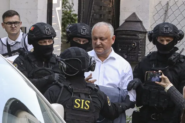 Members of Moldova's Information and Security service (SIS) escort former Moldovan President Igor Dodon to a van after he was detained at his house in Chisinau, Moldova, Tuesday, May 24, 2022. Moldovan media reported that police were conducting a search of a house described as belonging to Dodon, who served as president from 2016 to 2020. (Photo by Aurel Obreja/AP Photo)