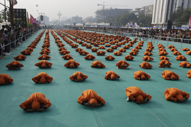 Indian school children perform yoga during the inauguration of an international kite festival in Ahmadabad, India, Tuesday, January 7, 2020. Kite flyers from various countries and across India are participating in the festival that is annually held on the Sabarmati riverfront in Ahmadabad. (Photo by Ajit Solanki/AP Photo)