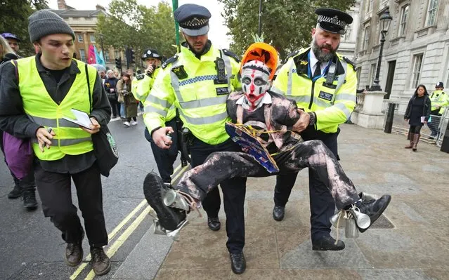 Police hold a protester during an Extinction Rebellion (XR) demonstration in Westminster, London on October 7, 2019. (Photo by Yui Mok/PA Images via Getty Images)