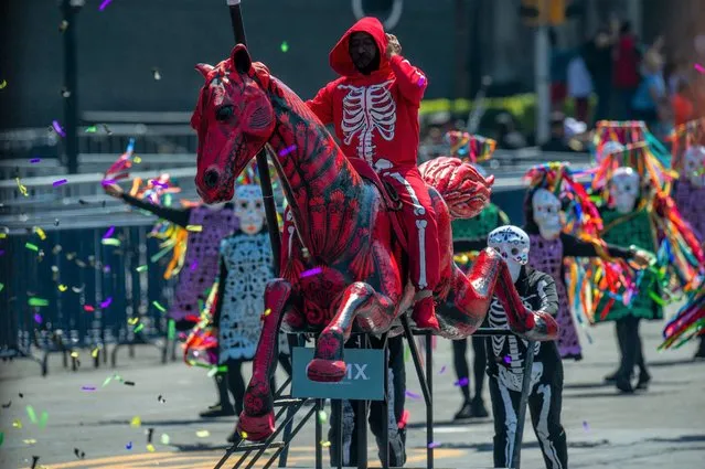 People on stilts take part in the Day of the Dead parade at Zocalo Square in Mexico City on October 31, 2021. (Photo by Claudio Cruz/AFP Photo)