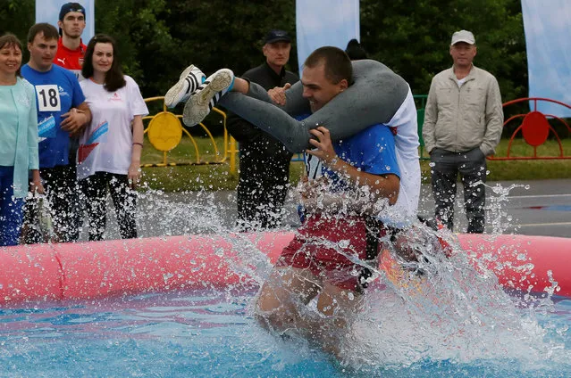 A man carries his wife over an obstacle while competing in the Wife Carrying Championship to mark City Day in Krasnoyarsk, Siberia, Russia, June 25, 2016. (Photo by Ilya Naymushin/Reuters)