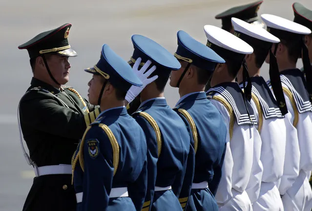 A commander adjusts the cap of a soldier before a welcoming ceremony in Beijing. (Photo by Petar Kujundzic/Reuters)