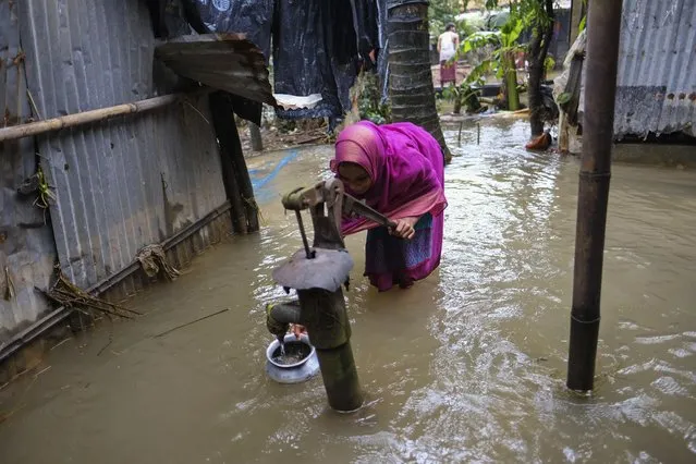 A flood-affected girl collects drinking water from an inundated water hand pump at Companygonj, in Sylhet, Bangladesh, Monday, June 20, 2022. With rising global temperatures due to climate change, experts say the monsoon is becoming more variable, meaning that much of the rain that would typically fall in a season is arriving in a shorter period of time. (Photo by Mahmud Hossain Opu/AP Photo)