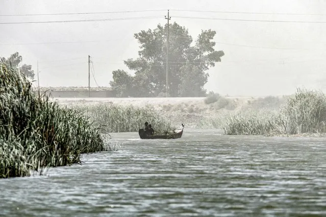 Boys sit in a boat during a dust storm in Iraq's southern marshes of Chibayish in Dhi Qar province on June 15, 2022. (Photo by Asaad Niazi/AFP Photo)