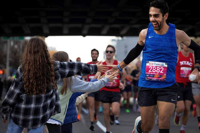 A participant high-fives children as he runs through the Brooklyn borough in New York on November 3, 2024. (Photo by Maye-E Wong/Reuters)