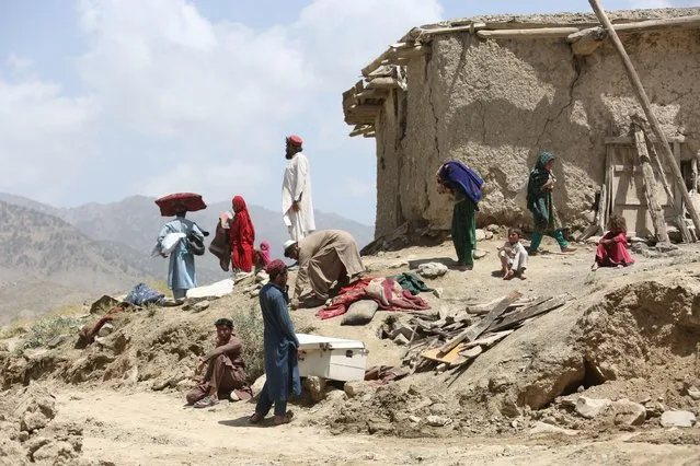 People stand near a house damaged in an earthquake in Paktika province, Afghanistan, on June 23, 2022. The Taliban-run administration in Afghanistan has called for international assistance amid ongoing rescue operations following the devastating earthquake Wednesday in the eastern area of the Asian country. (Photo by Saifurahman Safi/Xinhua News Agency/Alamy Live News)