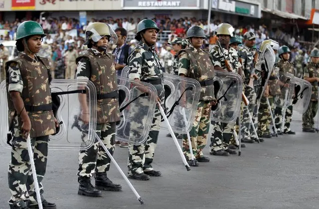 Paramilitary troopers stand guard during the funeral procession of Shwetang Patel in Ahmedabad, India, August 30, 2015. An Indian court in Gujarat state ordered crime investigators on Friday to investigate the death of 32-year old Patel, who allegedly died in police custody after he was taken away by the police during a protest. (Photo by Amit Dave/Reuters)