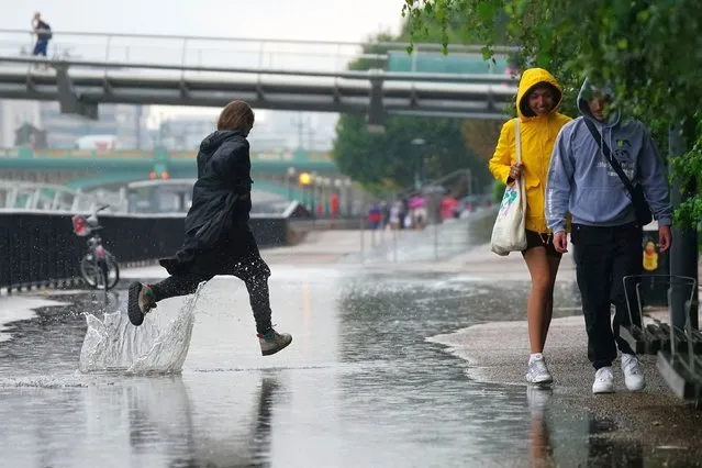 People running in the rain in London, Wednesday August 17, 2022.. After weeks of sweltering weather, which has caused drought and left land parched, the Met Office's yellow thunderstorm warning forecasts torrential rain and thunderstorms that could hit parts England and Wales. (Photo by Victoria Jones/PA Wire via AP Photo)
