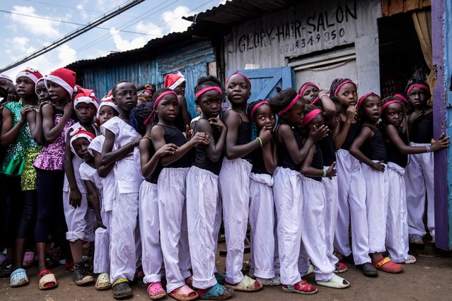 Young girls line up to get their makeup applied at a salon, prior to the start of a Christmas ballet event in Kibera slum, one of the busiest neighborhoods of Kenya's capital, Nairobi, Kenya Saturday, December 21, 2024. (Photo by Brian Inganga/AP Photo)