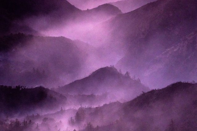 Smoke from the Eaton Fire lingers above the mountains of the Angeles National Forest north of Altadena, California, on January 13, 2025. Firefighters were battling massive wildfires on January 13 that have ravaged Los Angeles and killed at least 24 people, with officials warning of incoming dangerous winds that could whip up the blazes further. (Photo by Étienne Laurent/AFP Photo)