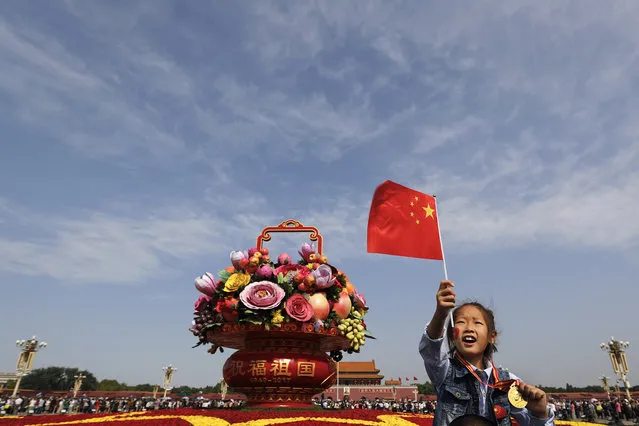 A Chinese girl sits on his father's shoulders near a giant basket decorated with replicas of flowers and fruits on display at Tiananmen Square on China's National Day in Beijing, Sunday, October 1, 2017. Hundreds of thousands foreign and domestic tourists flock to the square to celebrate the 68th National Day and the Mid-Autumn Festival over the week-long holidays. (Photo by Andy Wong/AP Photo)