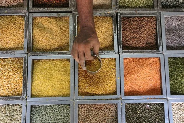 An employee collects lentils from a container inside a grocery store at a residential area in Mumbai, India, May 11, 2016. (Photo by Shailesh Andrade/Reuters)