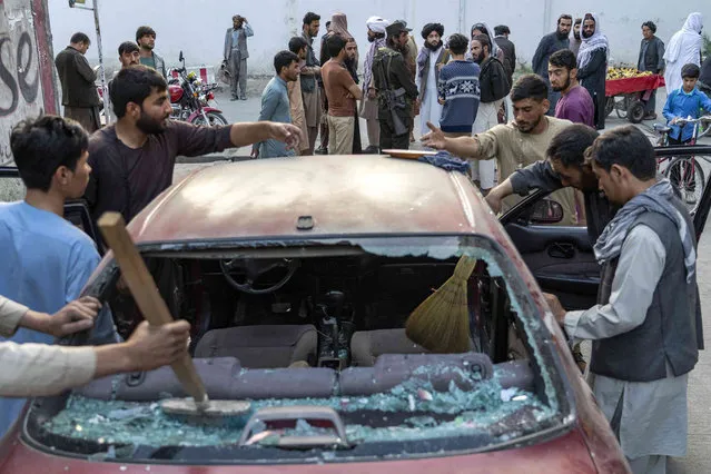 People clean a car that was damaged by an explosion, in Kabul, Afghanistan, Wednesday, September 21, 2022. The Taliban say at least three people have been killed and 13 others wounded in an explosion in the Afghan capital. The Taliban-appointed spokesman for Kabul's police chief said Wednesday the explosion occurred in a restaurant in the city's Dehmazang neighborhood. (Photo by Ebrahim Noroozi/AP Photo)