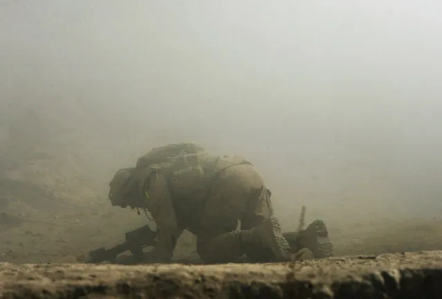 A wounded Canadian soldier from the NATO-led coalition crawls for cover seconds after his position was hit by a Taliban shell fired from an 82-millimeter recoilless rifle during an ambush in Zhari district of Kandahar province, southern Afghanistan, October 23, 2007. One Canadian soldier was lightly wounded and an Afghan National Army soldier was shot in the shoulder during heavy fighting in the volatile Mowz-e-Madad area of Kandahar province. (Photo by Finbarr O'Reilly/Reuters)