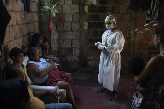 A health worker give instructions to members of Da Costa family after some of them tested positive for COVID-19 at their home in Manacapuru, Amazonas state, Brazil, Wednesday, June 3, 2020. (Photo by Felipe Dana/AP Photo)