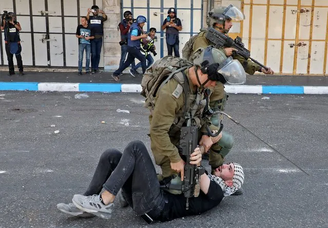 Israeli soldiers scuffle with a Palestinian during clashes in the flashpoint city of Hebron in the occupied West Bank on October 20, 2022. (Photo by Mosab Shawer/AFP Photo)
