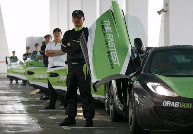 Drivers of taxi-booking app GrabTaxi's fleet of seven luxury cars pose for a photoshoot before they start picking passengers in Singapore September 15, 2015. The fleet of seven luxury cars, consisting of Porsche, Maserati, Aston Martin and McLaren cars, will be chauffeuring passengers for free within the city from Tuesday to Sunday during the Singapore F1 Grand Prix season. (Photo by Edgar Su/Reuters)