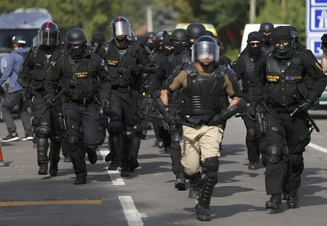 Hungarian riot policemen run as they are deployed at the border crossing with Serbia in Roszke, Hungary September 16, 2015. Hungarian riot police, backed by water cannon and armoured vehicles, moved into position at a border crossing on Wednesday where migrants were demanding they be allowed to cross from Serbia, a U.N. official at the scene told Reuters. (Photo by Dado Ruvic/Reuters)