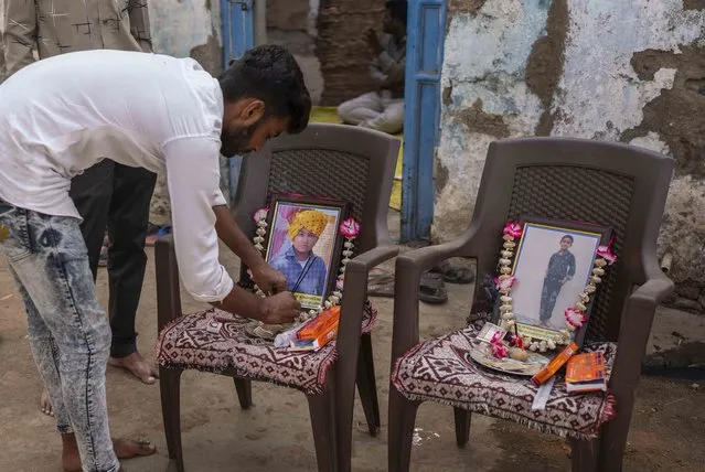 A relative puts incense sticks by the photograph of Yash Devadana 12, left, and his cousin Raj Baghwanji Bhai, 13, who died in a bridge collapse, outside their house in Morbi town of western state Gujarat, India, Tuesday, November 1, 2022. Sunday’s tragedy in Morbi has left the entire country shocked, with questions raised over why the pedestrian bridge, built during British colonialism in the late 1800s and touted by the state government as an “artistic and technological marvel”, collapsed just four days after months of repair. (Photo by Rafiq Maqbool/AP Photo)