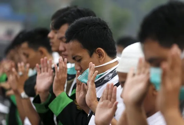 A group of Muslim students pray for rain to dissipate the haze, near Musi River in Palembang, on the Indonesian island of Sumatra, September 20, 2015. (Photo by Reuters/Beawiharta)