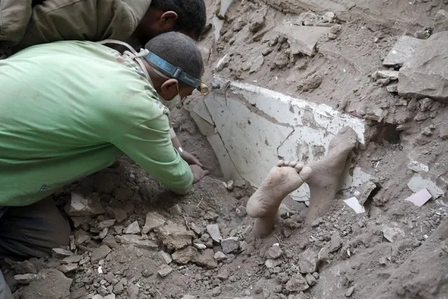 The feet of a child covered in dust are seen as people search for survivors under the rubble of a house destroyed by an air strike at the old quarter of Yemen's capital Sanaa, September 19, 2015. (Photo by Mohamed al-Sayaghi/Reuters)