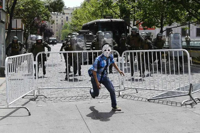 A Mapuche Indian activist runs away from riot policemen during a protest against Columbus Day in Santiago October 12, 2014. This year marks the 522th anniversary of Christopher Columbus' arrival to the Americas. Many indigenous people in Latin America consider it the day Columbus brought slavery, disease, colonisation and genocide from Europe to the Americas. (Photo by Ivan Alvarado/Reuters)