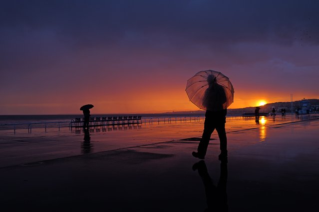 People walk on the “Promenade des anglais” at sunset on the french riviera city of Nice, on february 14, 2025. (Photo by Valery Hache/AFP Photo)