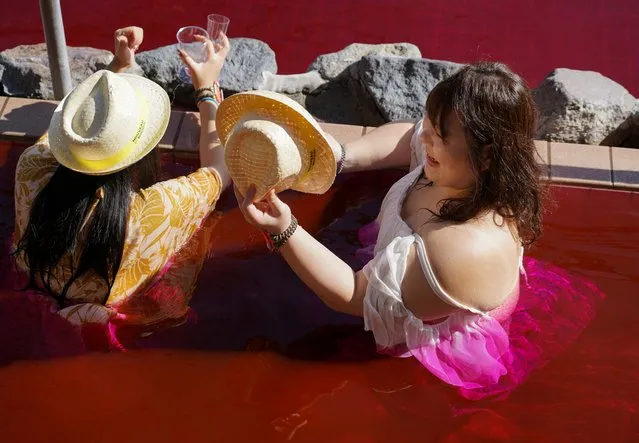 Women soaking in a hot bath with coloured water representing wine hold glasses of the 2022 Beaujolais Nouveau wine at the Hakone Kowakien Yunessun spa resort during an event marking Beaujolais Nouveau Day in Hakone, west of Tokyo, Japan on November 17, 2022. (Photo by Tom Bateman/Reuters)