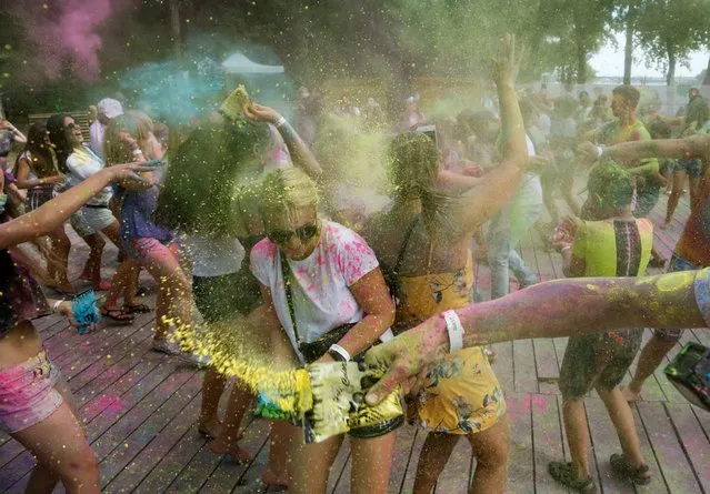 People throw colored powder on each other during the Holi Festival in a city park in Kyiv, Ukraine, Saturday, August 8, 2020. Ukrainians mark a popular ancient Hindu Holi Festival, also known as the festival of colors, or the festival of love, which signifies the victory of good over evil. Normally celebrated in spring, but postponed due to the coronavirus. (Photo by Efrem Lukatsky/AP Photo)