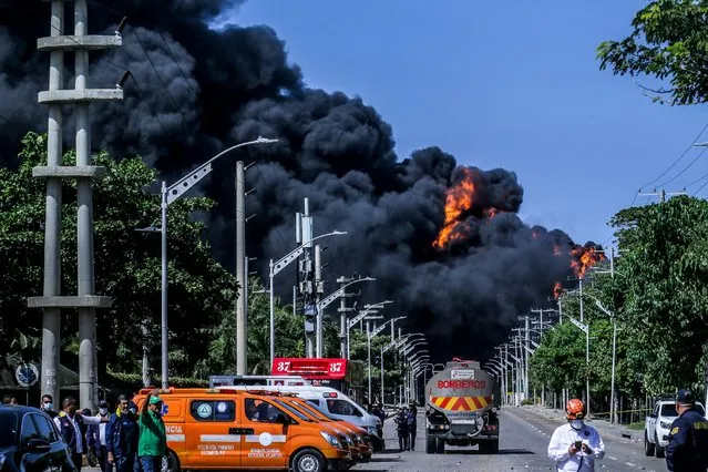 Black smoke rises from a fire at a hydrocarbon depot in Barranquilla, Colombia, on December 21, 2022. A firefighter died Wednesday while battling a fire in a hydrocarbon depot in the port city of Barranquilla, in northern Colombia, according to local authorities who are struggling to put out the intense flames. (Photo by Jesus Rico/AFP Photo)