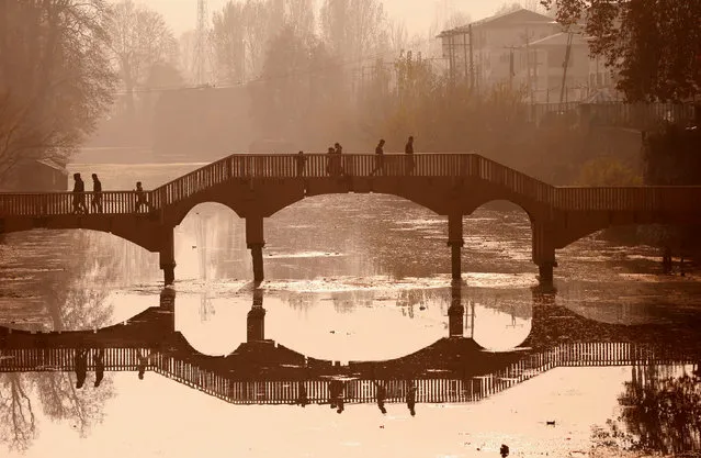 People walk on a wooden footbridge across a canal during an autumn day in Srinagar November 26, 2017. (Photo by Danish Ismail/Reuters)