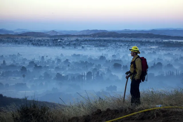 A firefighter watches a brush fire at the Apple Fire in Cherry Valley, Calif., Saturday, August 1, 2020. (Photo by Ringo H.W. Chiu/AP Photo)