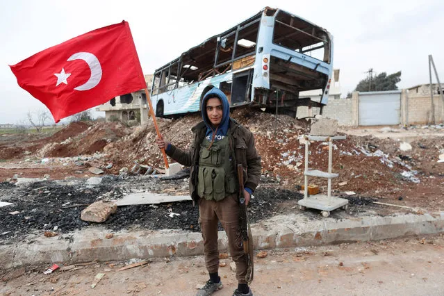A Turkey-backed Free Syrian Army fighter holds a makeshift Turkish flag as he patrols on a road near Azaz, Syria on January 21, 2018. (Photo by Osman Orsal/Reuters)