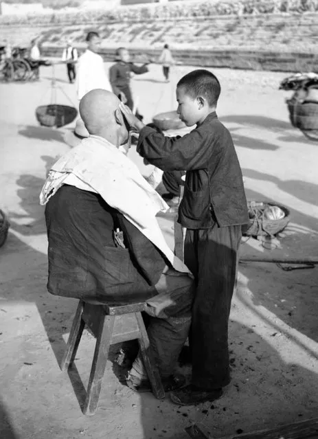 In China boys from 10 to 16 serve as barbers. Their shop is the open street, and anything serves as a chair, a haircut costs a penny, and a shave a half penny. The typical hairdresser's scene, in Peking, on October 23, 1936. (Photo by AP Photo)