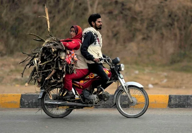 A woman carries firewood sitting on the back of a motorbike during the winter season in Islamabad, Pakistan, Saturday, January 21,2023. (Photo by Rahmat Gul/AP Photo)