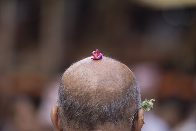 A devotee places a blessed flower on his head during the Rato Machindranath (Rain God) festival in Patan, Nepal, 13 May 2025. Hindus and Buddists in Nepal celebrate Ratomachindranath festival by pulling a 60-feet-high wooden chariot all over the valley for a month. The festival is observed annually to bring good rainfall, good harvest, prosperity and good fortune for the coming years. (Photo by Narendra Shrestha/EPA)