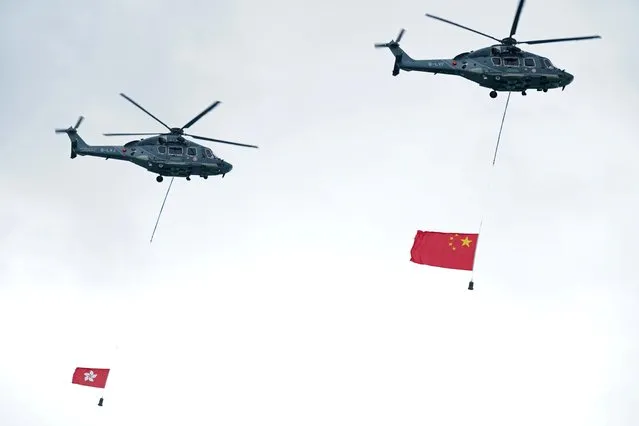 Helicopters fly the flags of China (R) and Hong Kong Special Administrative Region during a flag-raising ceremony marking China's National Day at Golden Bauhinia Square in Hong Kong, China on October 1, 2020. (Photo by Lam Yik/Reuters)