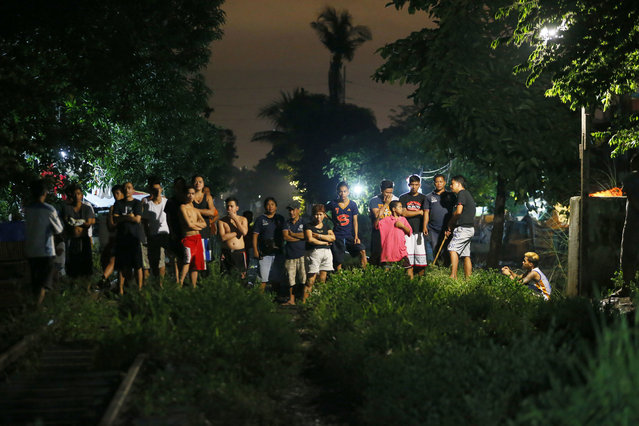 Residents are kept at a distance as police investigators examine the bodies of three suspects who were killed in a sting operation by the authorities in the continuing “War on Drugs” campaign of Philippine President Rodrigo Duterte before dawn Friday, September 30, 2016 in Caloocan city, north of Manila, Philippines. Duterte raised the rhetoric over his bloody anti-crime war to a new level Friday, comparing it to Hitler and the Holocaust and saying he would be “happy to slaughter” 3 million addicts. (Photo by Bullit Marquez/AP Photo)