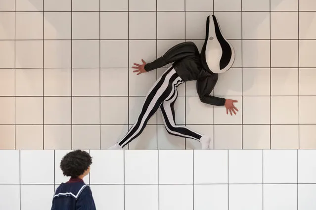 A performer in a squash- like costume as part of a new work of art by Anthea Hamilton, during a press pre- view at the Tate Britain in London, Wednesday, March 21, 2018. Over 7000 white tiles have been laid in the large galley with selected works from the Tate' s collection, chosen for their organic form, the tiles formed in to podiums which the performer uses to interact with the work. (Photo by Stephen Chung/Alamy Live News)