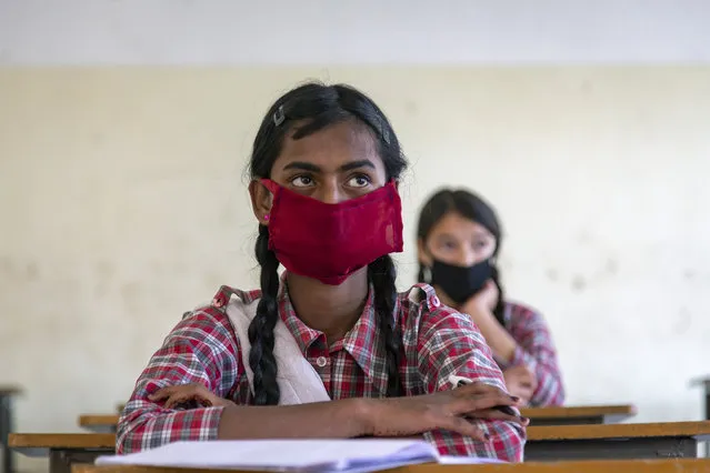 Students wear masks and sit following social distancing measures as a precautionary measure against the coronavirus, as they attend a class at the Government Senior Secondary School in Dari, near Dharmsala, India, Friday, November 6, 2020. (Photo by Ashwini Bhatia/AP Photo)