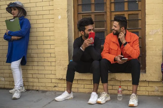 Young men chat near Al-Mutanabbi street in Baghdad, Iraq, Friday, February 24, 2023. (Photo by Jerome Delay/AP Photo)