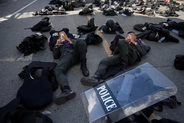 Police officers use their mobile phones near the Crown Property Bureau ahead of a pro-democracy rally demanding Thailand's King Maha Vajiralongkorn hands back royal assets to the people and reforms on the monarchy, in Bangkok, Thailand, November 25, 2020. (Photo by Chalinee Thirasupa/Reuters)