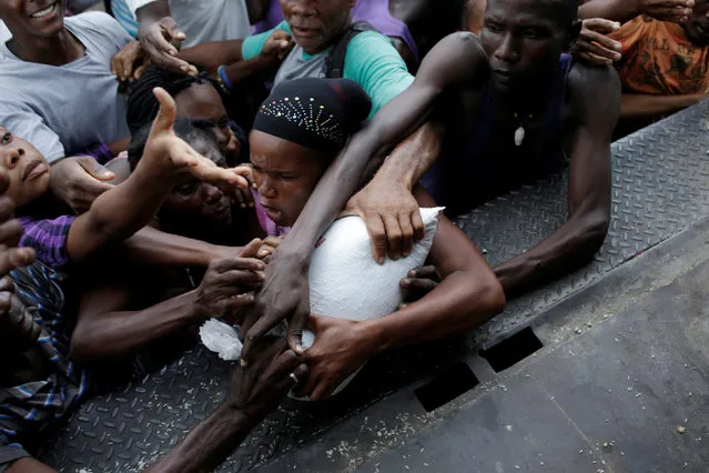Residents fight for a sack filled with food at the end of a food distribution after Hurricane Matthew in Saint Jean du Sud, Haiti, October 16, 2016. (Photo by Andres Martinez Casares/Reuters)