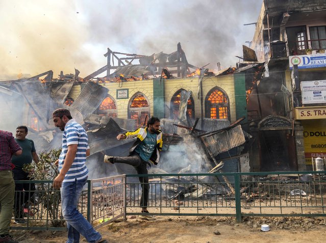 Civilians work to extinguish a fire in Srinagar, Indian controlled Kashmir, Monday, June 24, 2024. A mosque and some buildings were damaged in the fire. Some people were injured in this incident. (Photo by Mukhtar Khan/AP Photo)