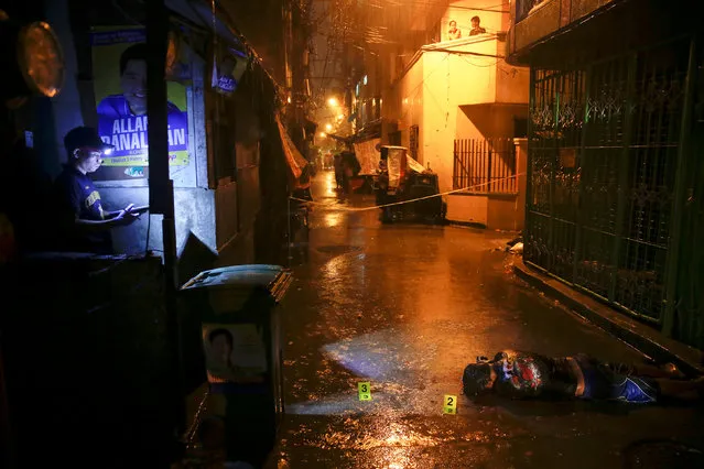 Heavy rain pours as police investigate inside a narrow alley where a man was killed by unidentified gunmen riding motorcycles in Manila, Philippines early October 11, 2016. (Photo by Damir Sagolj/Reuters)