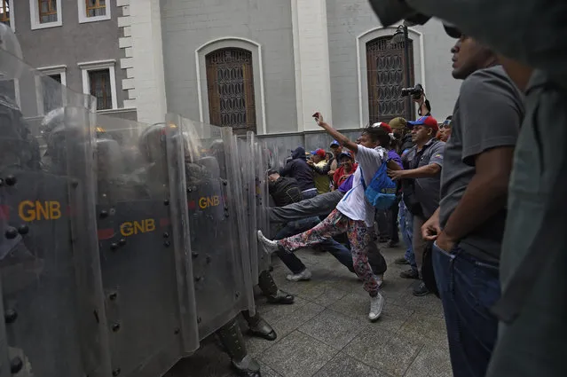 Supporters of Venezuelan Government clash with riot police before the National Assembly in Caracas on October 27, 2016. Venezuela's opposition ratchets up the pressure on President Nicolas Maduro at mass protests, announcing plans for a general strike, a new march and a legislative onslaught. (Photo by Juan Barreto/AFP Photo)