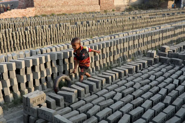A child plays with a tire in a brick factory in Munshiganj near Dhaka, Bangladesh March 9, 2018. (Photo by Mohammad Ponir Hossain/Reuters)
