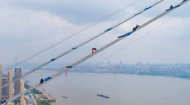 This photo taken on May 8, 2018 with a drone shows workers labouring on the construction of a double-deck suspension bridge crossing the Yangtze River in Wuhan in China's central Hubei province. (Photo by AFP Photo/Stringer)