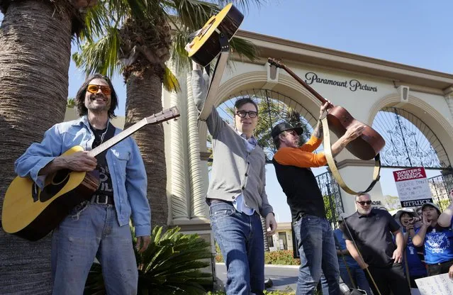 From left, Brian Bell, Rivers Cuomo and Scott Shriner of the rock band Weezer perform for striking members of the Writers Guild during a rally in front of Paramount Pictures studio, Wednesday, May 17, 2023, in Los Angeles. (Photo by Chris Pizzello/AP Photo)