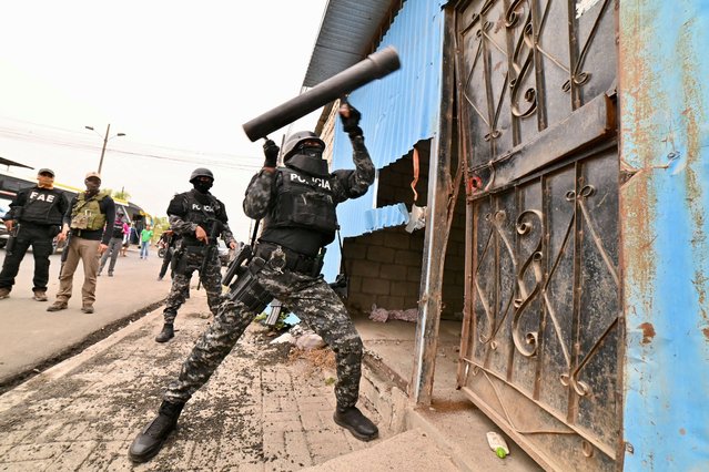 A police officer opens a door to search a house during a police operation in Duran, Ecuador on November 27, 2024. After the police operation, four houses were demolished and 13 alleged members of the “Chone Killers“ gang were arrested, according to police. (Photo by Marcos Pin/AFP Photo)